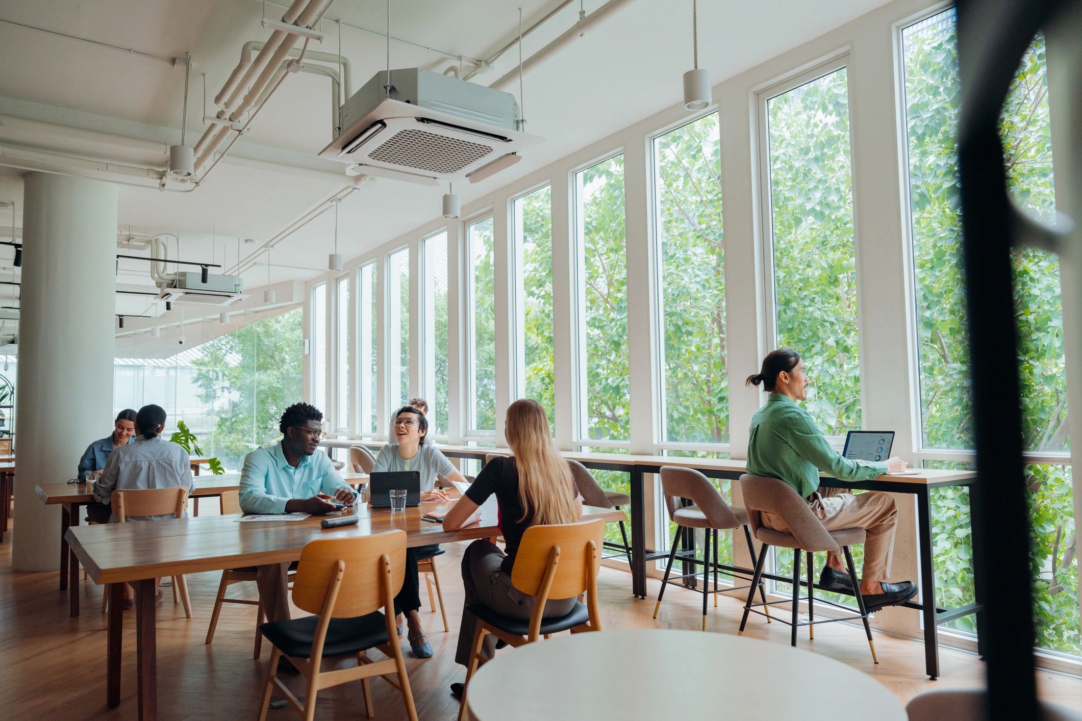 Diverse professionals working in modern coworking space with large windows